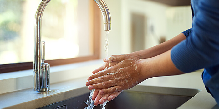 Pessoa lava as mãos com água corrente, reforçando a importância da higiene pessoal para prevenir doenças.