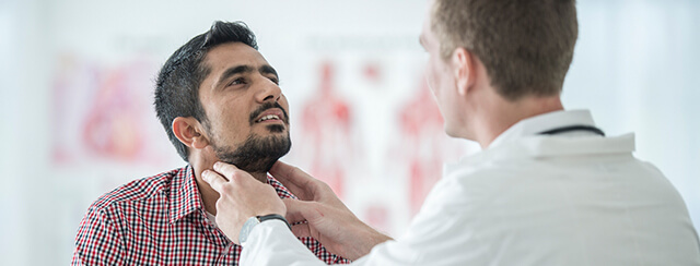 Médico examina o pescoço de um paciente para verificar possíveis sinais de doenças da tiroide.