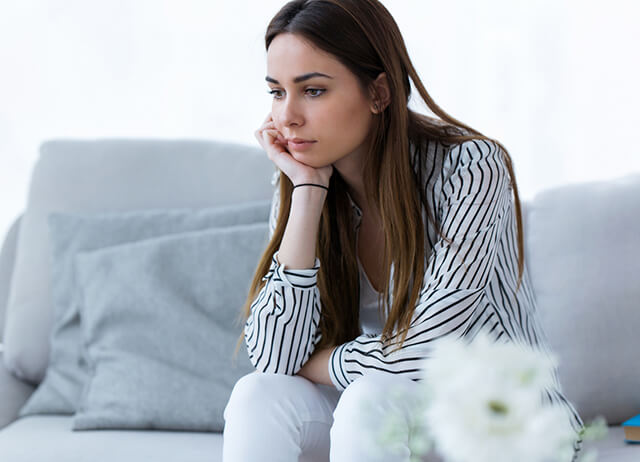 Mulher com expressão preocupada, sugerindo desconforto e sintomas da candidíase vaginal.