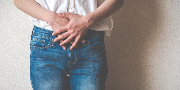 Pessoa com as mãos na região abdominal, demonstrando desconforto típico de uma infeção urinária.