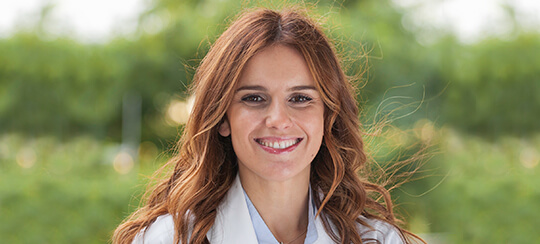 Dra. Ana Miranda, médica especialista, sorrindo em ambiente externo, destacando os cuidados a ter com o consumo de antibióticos.