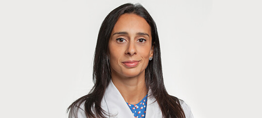 Dra. Claúdia Ribeiro de Jesus, médica especialista sorrindo, destacando as causas, sintomas e tratamento da pneumonia.