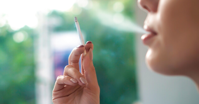 Mulher a fumar um cigarro na rua. Uma das principais causas da dpoc.