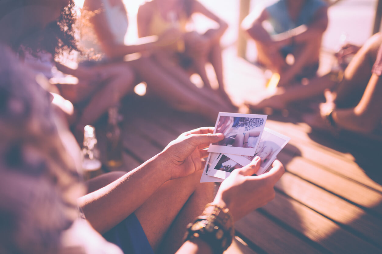 Um grupo de amigos reunidos ao ar livre a partilharem memórias através de registos fotográficos e do convívio.