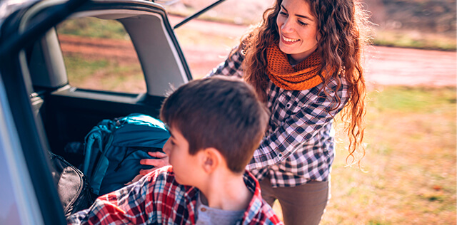 Uma mãe e o seu filho a arrumarem a mala do carro, prontos para irem de férias.