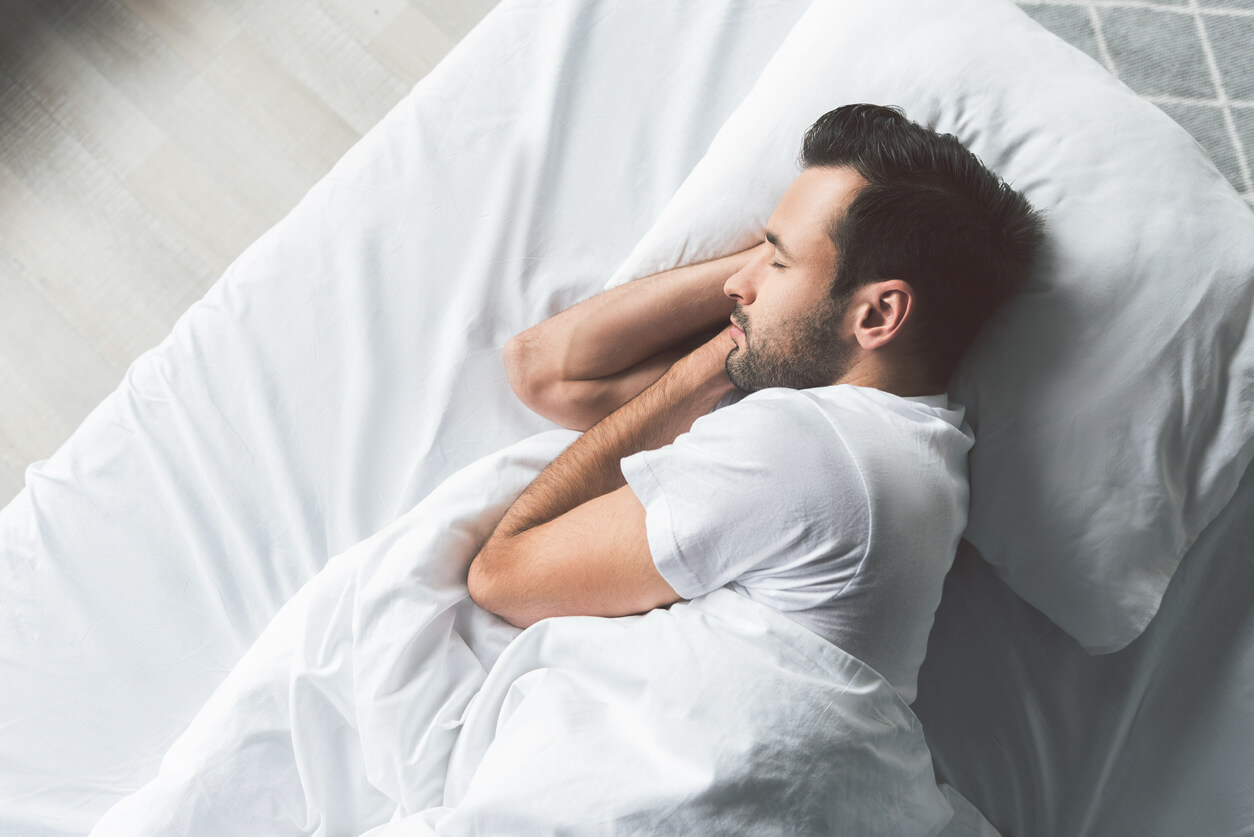 Homem deitado na sua cama, sinal da importância de uma boa noite de sono para a nossa saúde.